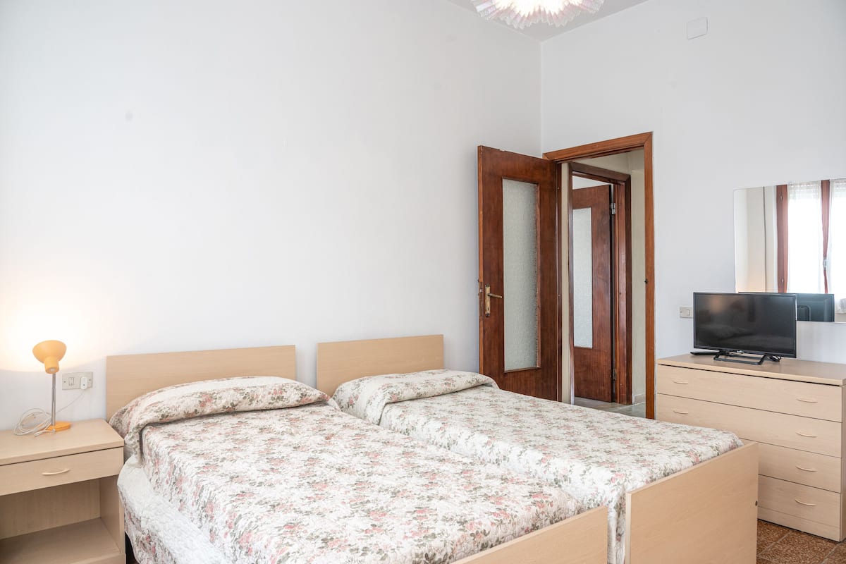 Ein Schlafzimmer mit zwei Betten, einem Fernseher, einem Schminktisch und einer Tür.