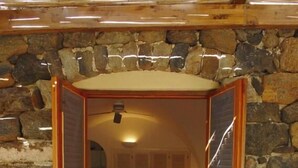 Un dormitorio con pared de piedra, una cama y techo de madera.