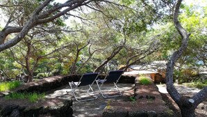 Un área de estar al aire libre y apartada, con un muro de piedra y un banco de madera.