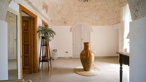 A spacious room with a large vase on a round mat, a wooden chair, and a plant. - Wonderful Trulli building in Locorotondo countryside (Locorotondo)