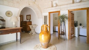 A room with a stone wall, a wooden desk, a large vase, and a bed. - Wonderful Trulli building in Locorotondo countryside (Locorotondo)