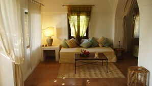Une chambre confortable avec un lit, une table de chevet, une lampe et une vue sur l’extérieur à travers une fenêtre avec des rideaux.