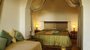 Une chambre à coucher avec un grand lit, deux tables de chevet avec des lampes et un ventilateur de plafond.
