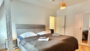 Ein modernes Schlafzimmer mit einem großen Bett, einem Kleiderschrank und einer Deckenleuchte.