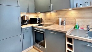 Eine moderne Küche mit grauen Schränken, einer Holz Arbeitsplatte und einem eingebauten Backofen.