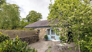 A stone house with a blue door and a small patio area with a table and chairs. - The Cow Shed—Luxury Barn Moments From Narberth (Narberth)