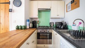 A compact kitchen with white cabinets, a stainless steel stove, and a sink with a dish rack.