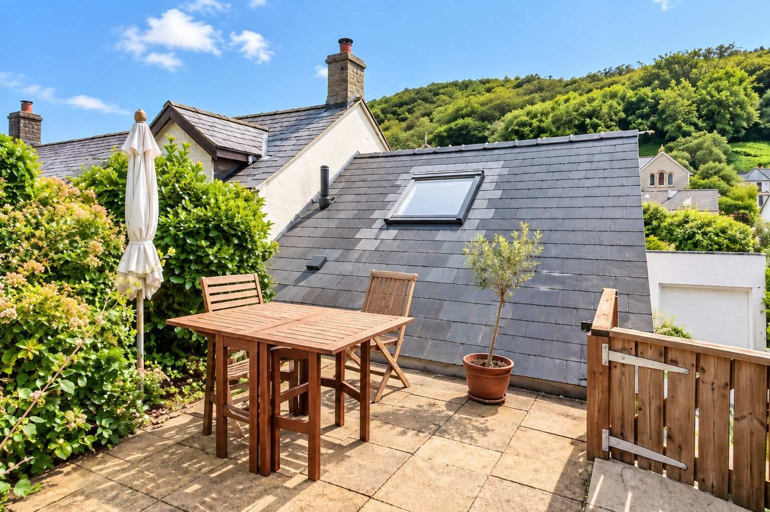 Une terrasse avec une table et des chaises, une plante en pot et une clôture en bois.