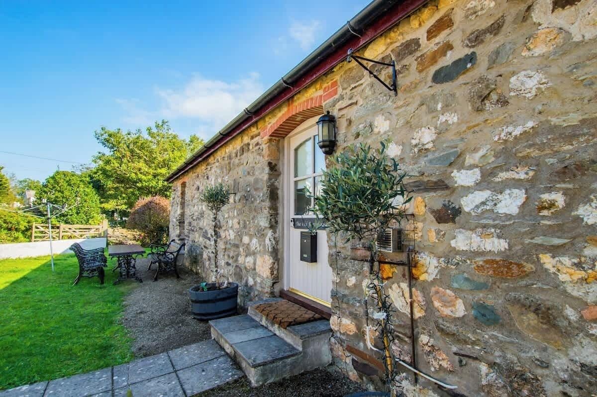 A stone building with a white door, a small porch with steps, and outdoor seating.