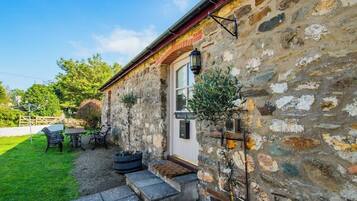 A stone building with a white door, a small porch with steps, and outdoor seating.