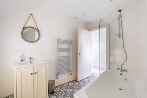 Relax in a spacious bathroom with a bathtub, showerhead, and vanity with mirror.