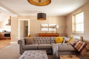 Relax in this stylish living room with a tufted sofa, pendant light, and wooden coffee table.