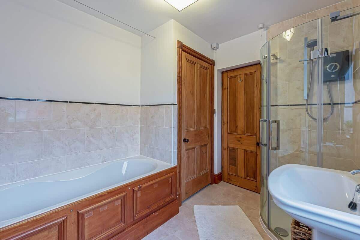 A modern bathroom with a freestanding bathtub, a glass-enclosed shower, and wooden cabinetry.