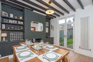 A dining area with a wooden table set for six, a dark wall with shelves, and a large mirror.