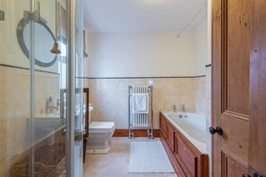 A modern bathroom with a glass shower enclosure, a toilet, a bathtub, and a wooden vanity.