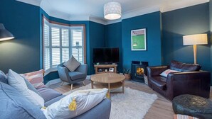 A living room with a blue wall, a fireplace, a television, and a sofa.