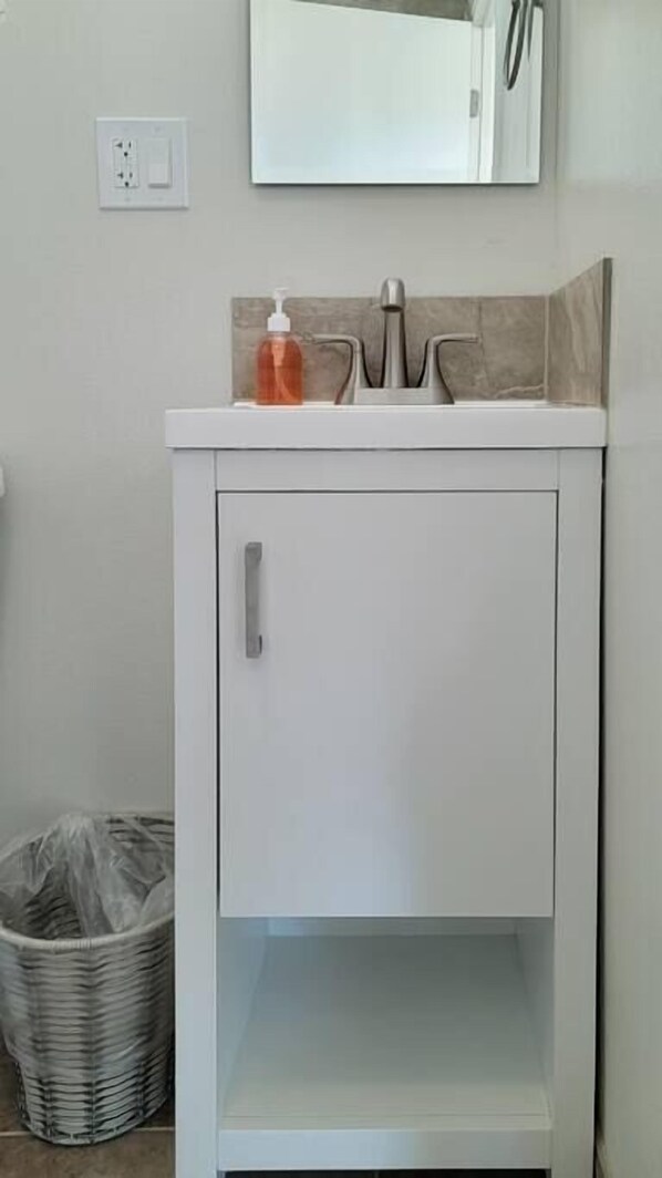 Un armario blanco con una sola puerta y un pequeño estante debajo.
