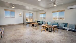 A spacious living area with a large window, a ceiling fan, and a sofa with cushions.