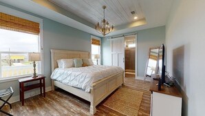 A bedroom with a bed, a bedside table, a chair, a dresser, a mirror, and a window.