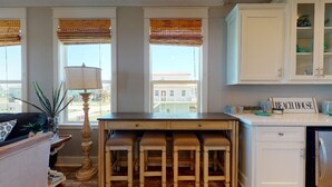 A kitchen with a bar area, a dining table, and a refrigerator.