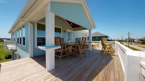 Une maison située sur la côte, dotée d’une terrasse en bois, d’un porche abrité et d’un coin repas avec du mobilier d’extérieur.