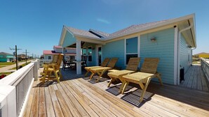 A wooden deck with lounge chairs and a covered area.