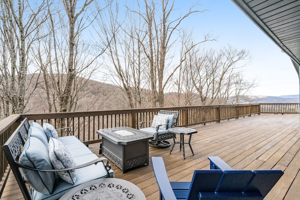 A wooden deck with outdoor furniture including a sofa, chairs, and a table. - Stunning 2-level mountain home, game room, furnished decks, firepit (Banner Elk)