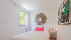 A bedroom with a bed, a nightstand, a wall clock, a window, and a decorative mirror. - Melro's Places (Setúbal)