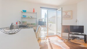 A modern kitchen with a dining area, a TV, and a balcony with a view. - Melro's Places (Setúbal)