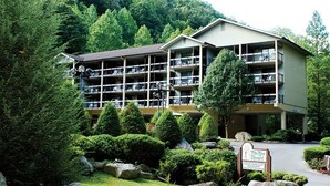 Un hotel de varios pisos con balcones, rodeado de exuberante vegetación y montañas al fondo.