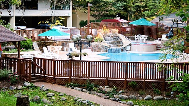Un patio trasero con piscina, bañera de hidromasaje y una cascada.