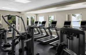 Une salle de sport équipée de tapis de course, d’appareils de musculation et d’autres équipements d’exercice.