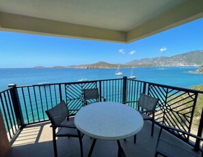 Enjoy the sea view from this balcony with a round table and two chairs.