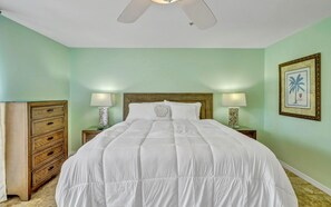 A neatly made bed with a wooden headboard, two bedside lamps, and a framed picture on the wall.