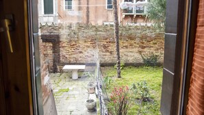 A courtyard with a stone bench, potted plants, and a brick wall. - CA SORANZO (Venice)