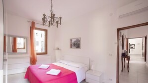 A bedroom with a bed, nightstands, a chandelier, a window with curtains, and a door leading to a bathroom. - CA SORANZO (Venice)