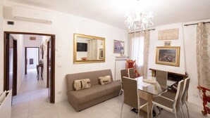 A living room with a sofa, dining table, chairs, and a chandelier. - CA SORANZO (Venice)