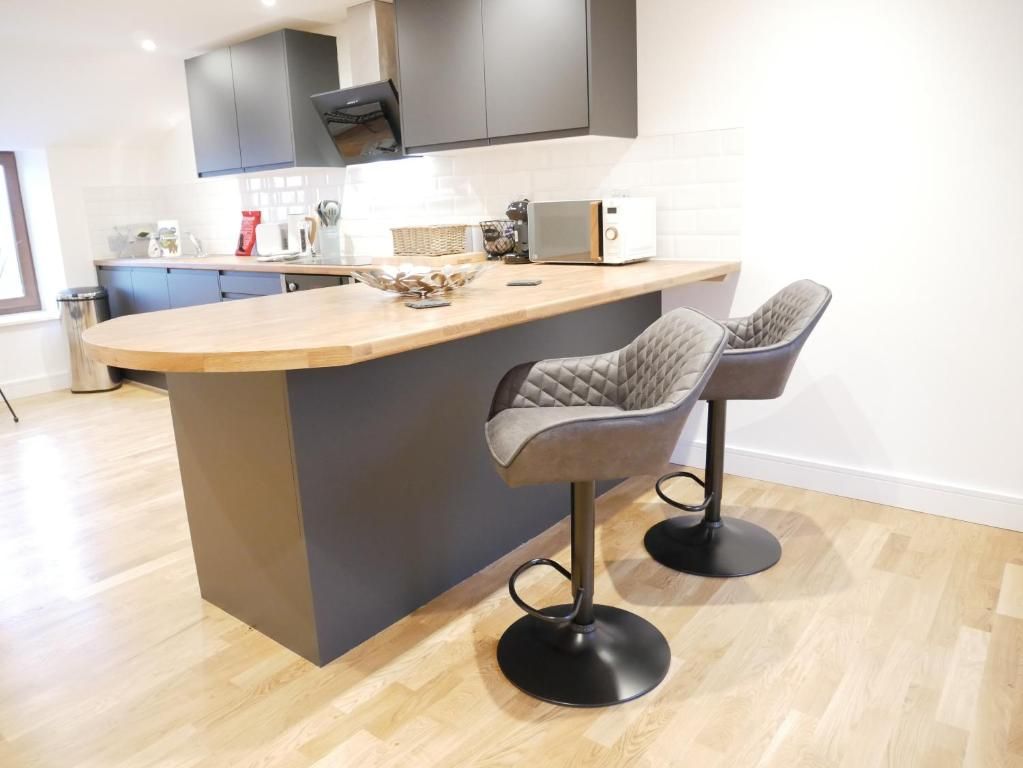 A modern kitchen with a central island, two bar stools, and a microwave.