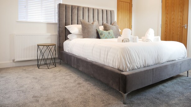Une chambre moderne avec un grand lit, une table de chevet, un radiateur et une porte en bois.