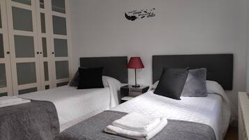 Una habitació d'hotel amb dos llits, una cambrera de nit amb una làmpada i una decoració mural.
