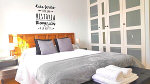 A neatly made bed with a headboard, pillows, and a blanket. There is a wall with a sign above the bed.