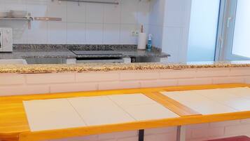 Una cocina moderna con armarios blancos, encimeras de granito y electrodomésticos de acero inoxidable. Hay dos taburetes rojos y una isla central con encimera de madera.