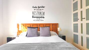 Een hotelkamer met een bed, twee kussens, een nachtkastje met een lamp en een inloopkast met ruitverdelingen.