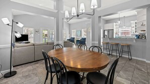 Una cocina moderna con una isla central, taburetes de bar y una mesa de comedor con sillas.