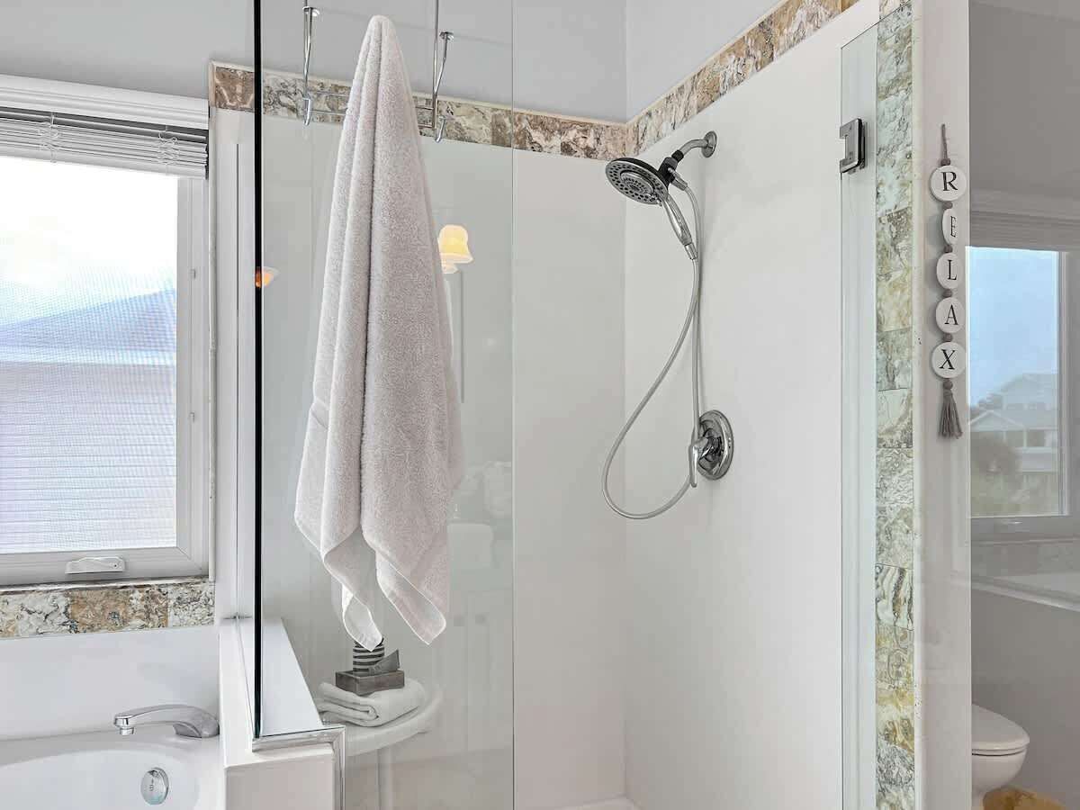 Ein modernes Badezimmer mit einer gläsernen Dusche, einem weißen Waschbecken und einem Handtuch an einem Halter.