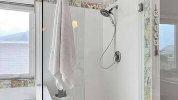 Ein modernes Badezimmer mit einer gläsernen Dusche, einem weißen Waschbecken und einem Handtuch an einem Halter.