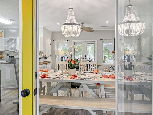 A modern dining area with a glass partition, a ceiling fan, and pendant lighting.
