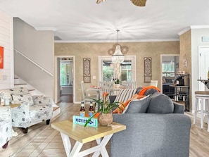 A living room with a grey sofa, a wooden coffee table, and a staircase. - Tangerine Cove-5 Min 2 Beach-Golf Cart Deals (Destin)