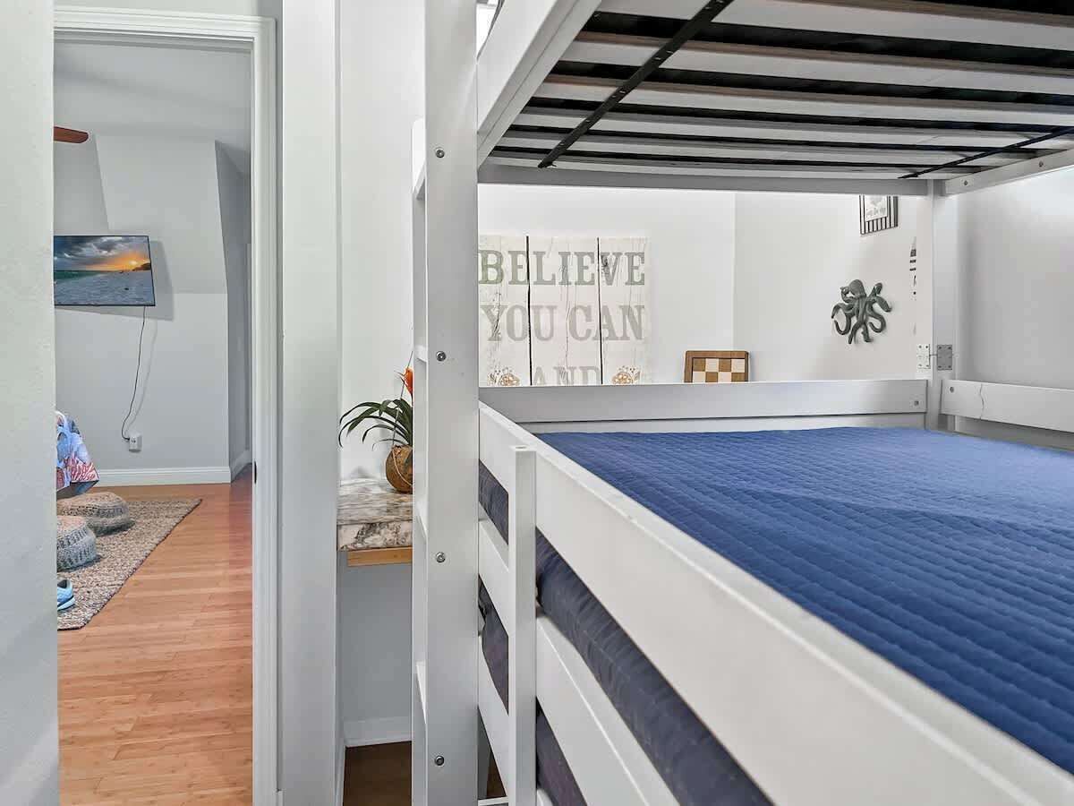 A bunk bed with a blue mattress, a motivational poster, and a small plant.