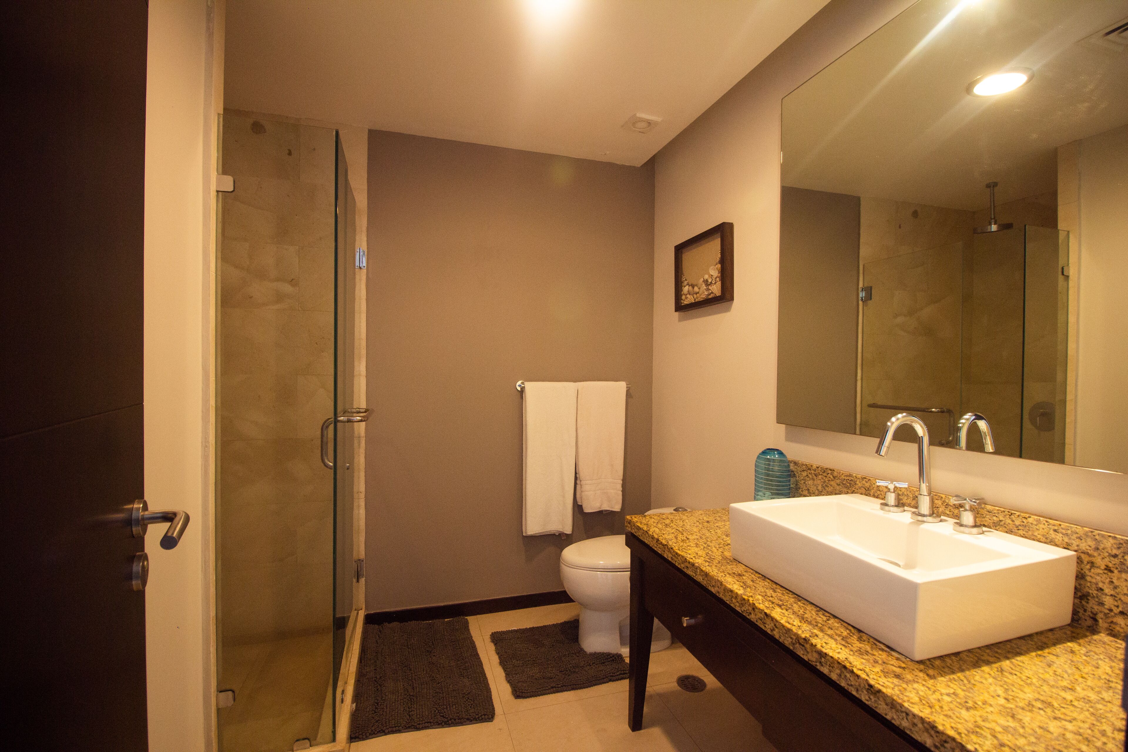 A bathroom with a glass shower enclosure, a white sink, and a large mirror.